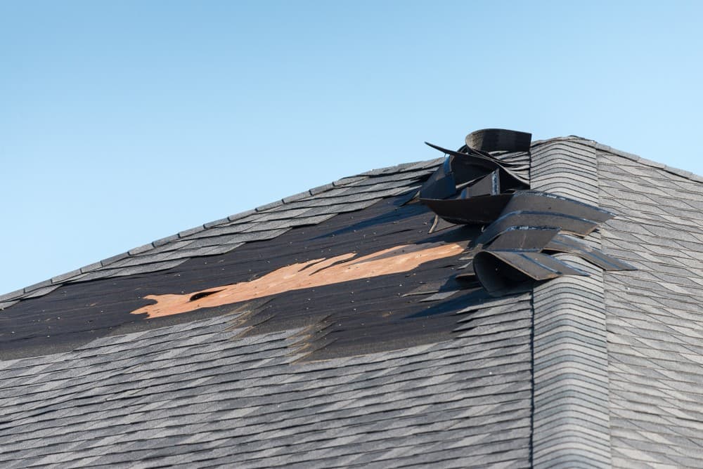 Close-up aerial detail of lifted roof tiles and storm damage